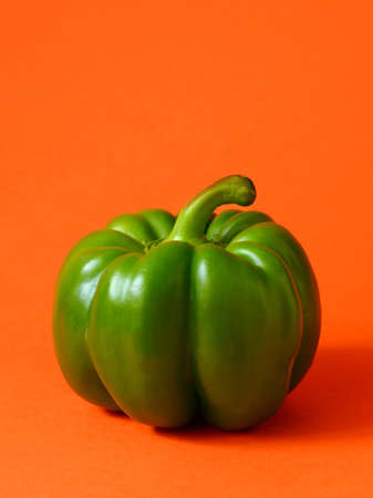 Green bell pepper on orange colored backgroundの写真素材