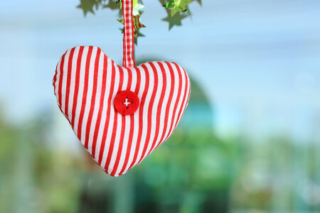 Red heart fabric hanging on glass backgroundの写真素材