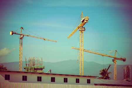Construction site with cranes on sky background, retro tone imageの写真素材