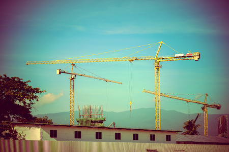 Construction site with cranes on sky background, retro tone imageの写真素材