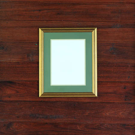 gold photo frame on wood wall backgroundの写真素材