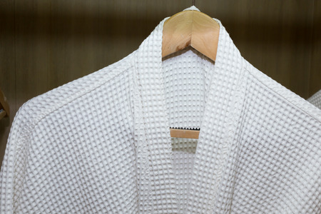 white bathrobes hanging in wooden closetの写真素材