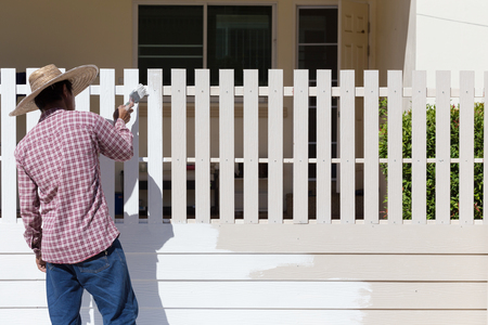 worker painted white fence with brushの写真素材