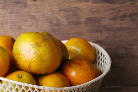 orange fruit in white basket on wood table backgroundの写真素材