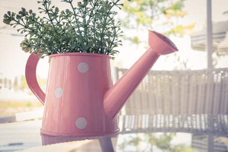 flowers vase decorated on mirror table at living room, artificial flowers in vase watering canの写真素材