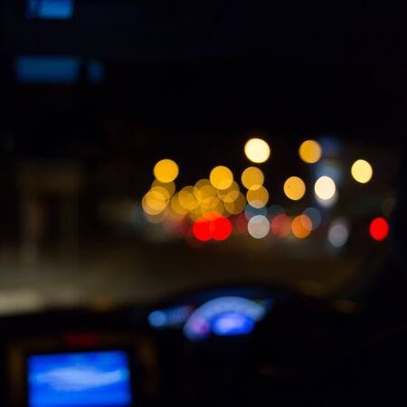 abstract blurred view of driver looking inside car on night road with light trafficの写真素材