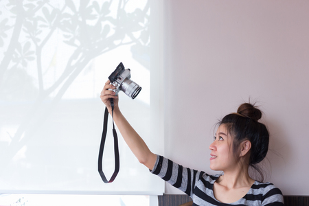 asian woman take a photo selfie with mirrorless digital cameraの写真素材