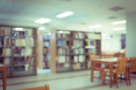 bookshelf and table desk in library, education abstract blur defocused background