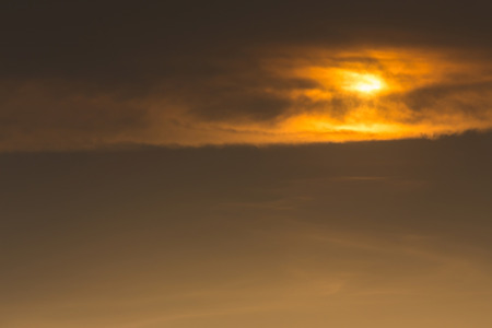 golden sky with clouds cover sunの写真素材