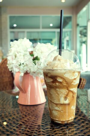 iced frappe coffee in plastic mug put on the rattan weave table in coffee shop cafeの写真素材