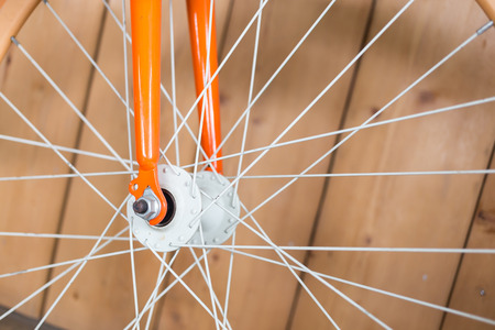 orange bicycle parked with wood wall, close up image part of bicycleの写真素材