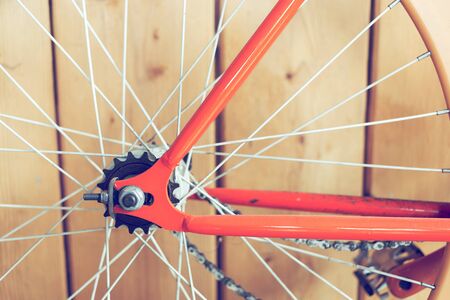 orange bicycle parked with wood wall, close up image part of bicycleの写真素材
