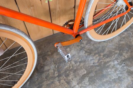 orange bicycle parked with wood wall, close up image part of bicycle