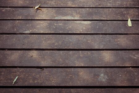 old wooden walkway with falling leaves in the morning of autumn seasonal