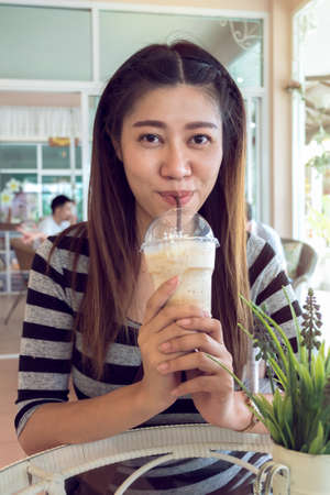 happy women drinking frappe coffee in cafeの写真素材