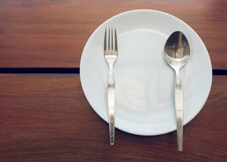 dishware set on wood table with plate, spoon and fork, image used filter vintage