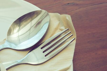 dishware set on wood table with plate, spoon and fork, image used filter vintageの写真素材