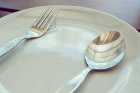 dishware set on wood table with plate, spoon and fork, image used filter vintageの写真素材