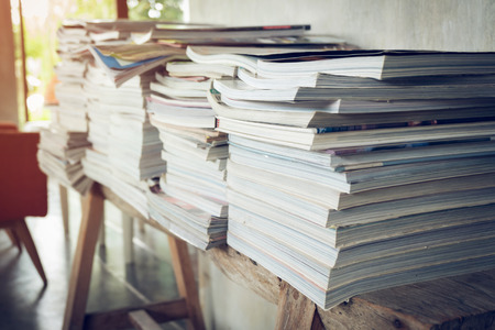 stack of magazine book on wooden table shelf in living room with sofa furniture