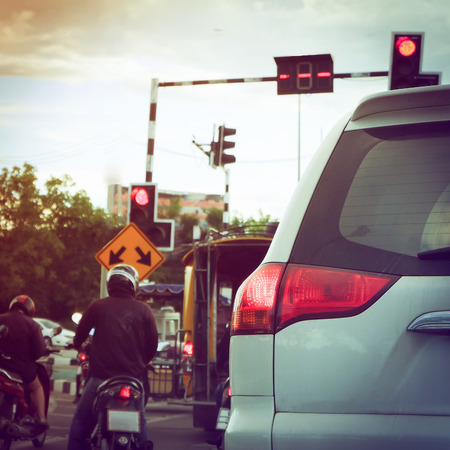 close-up part of tail light of car on urban road with people ride motorcycle stop traffic light on streetの写真素材