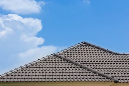 black tile roof of house with blue sky and cloud backgroundの写真素材