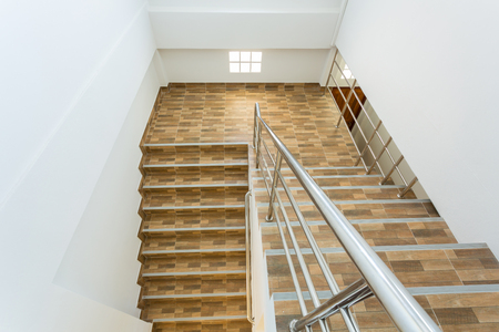 staircase in residential house with stainless steel banister, ceramic floor tiles wood patternの写真素材