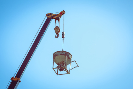 machinery crane hoisting cement mortar mixer bucket container in construction site building industryの写真素材