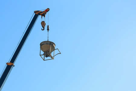 machinery crane hoisting cement mortar mixer bucket container in construction site building industryの写真素材