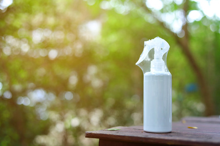white blank foggy water spray bottle of product package on wood display with abstract blur green...