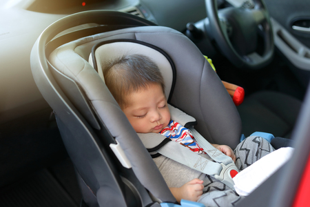 cute baby boy sleeping in car seat safety belt lock protection drive road trip travelの写真素材
