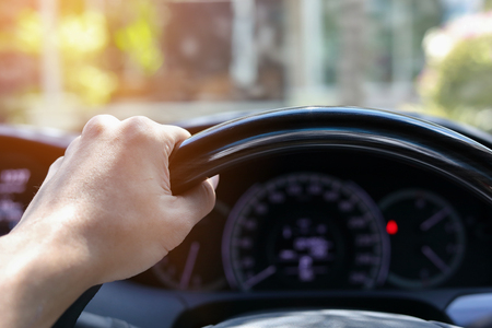 man hand holding control steering wheel of drive vehicle car road trip travel in the morning dayの写真素材