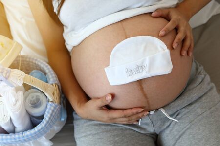 cute baby hat put on mother tummy pregnant awaiting for newbornの写真素材