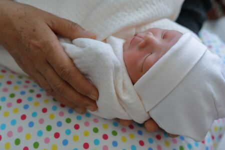 grandmother old hand holding cute baby newborn of grandchild with love