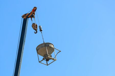 machinery crane hoisting cement mortar mixer bucket container in construction site building industryの写真素材