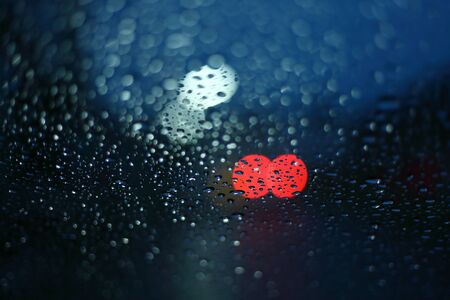 water rain drop on glass window with blur street light in night town backgroundの写真素材
