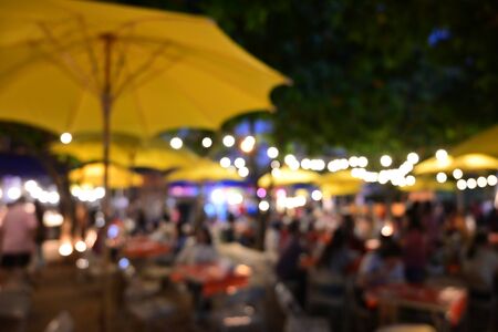 people crowd in night party festival of outdoor garden with light bulb hanging decoration, image blur used for celebration backgroundの写真素材