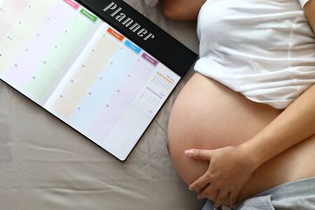 mother pregnant maternity hand hug tummy with love a baby, mom write planner schedule note happy memoriesの写真素材