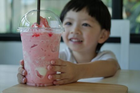 happy cute boy drink strawberry smoothie fruitの写真素材