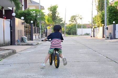 cute boy riding balance bike on streetの写真素材