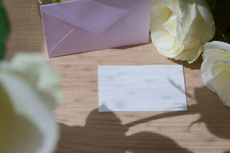 blank white paper of wedding card put on wooden table with romantic rose flower in morning day,...