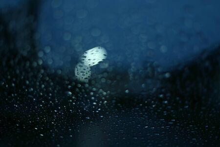 water rain drop on glass window with blur street light in night town background