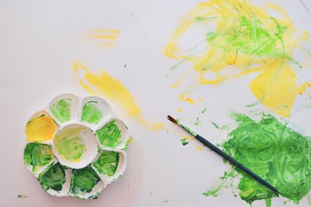 baby using green and yellow watercolor painting on white paper with colorful abstract imaginationの写真素材