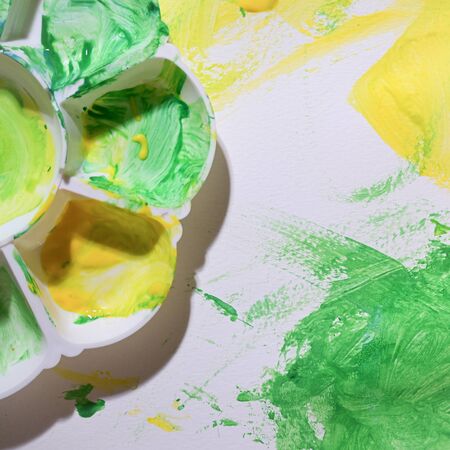 baby using green and yellow watercolor painting on white paper with colorful abstract imaginationの写真素材