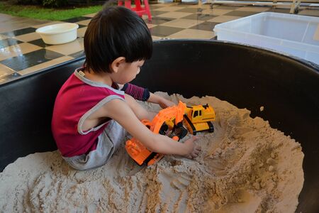 child boy play construction vehicle toy in sand playgroundの写真素材