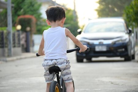 kid riding balance bike on road with car driving, image danger accident conceptの写真素材