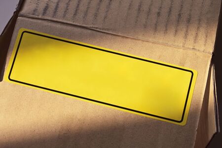 blank yellow label sticker tab of warning sign on carton paper boxの写真素材