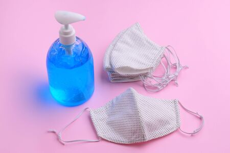 fabric face mask and alcohol gel bottle sanitizer on pink backgroundの写真素材