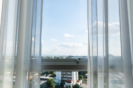 white curtain on glass window with view of city in the room