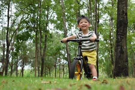 happy kid playing balance bike in nature parkの写真素材