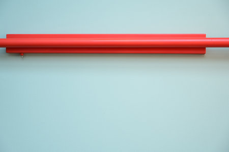 red water pipe on light blue wall, construction industryの写真素材